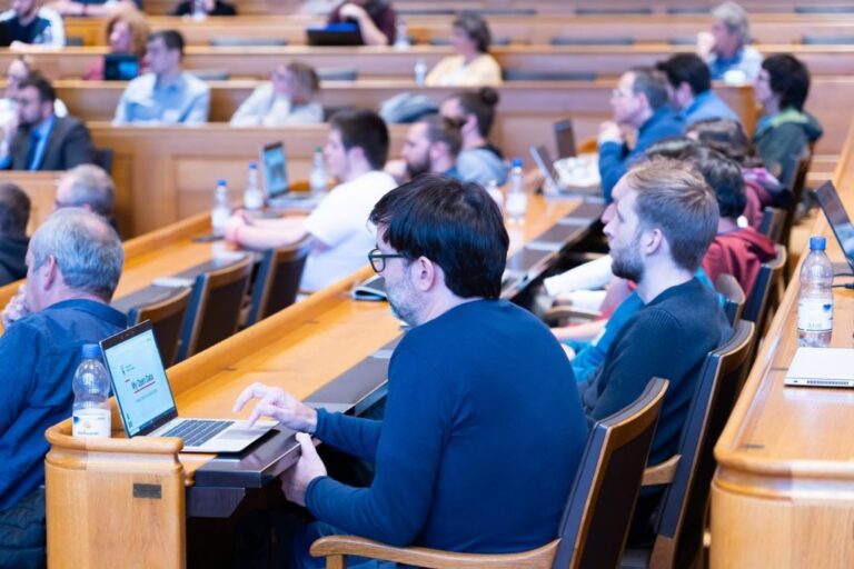 Audience with laptops in the council benches