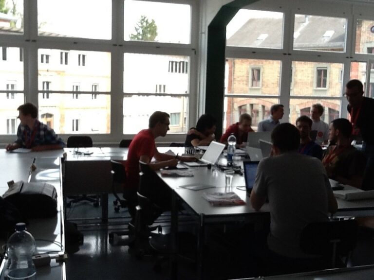 Teams an Tischen vor den Fenstern eines Seminarraums