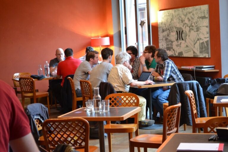 Participants at tables in a room with red walls