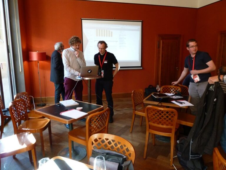 Teams at tables, two participants standing at the front
