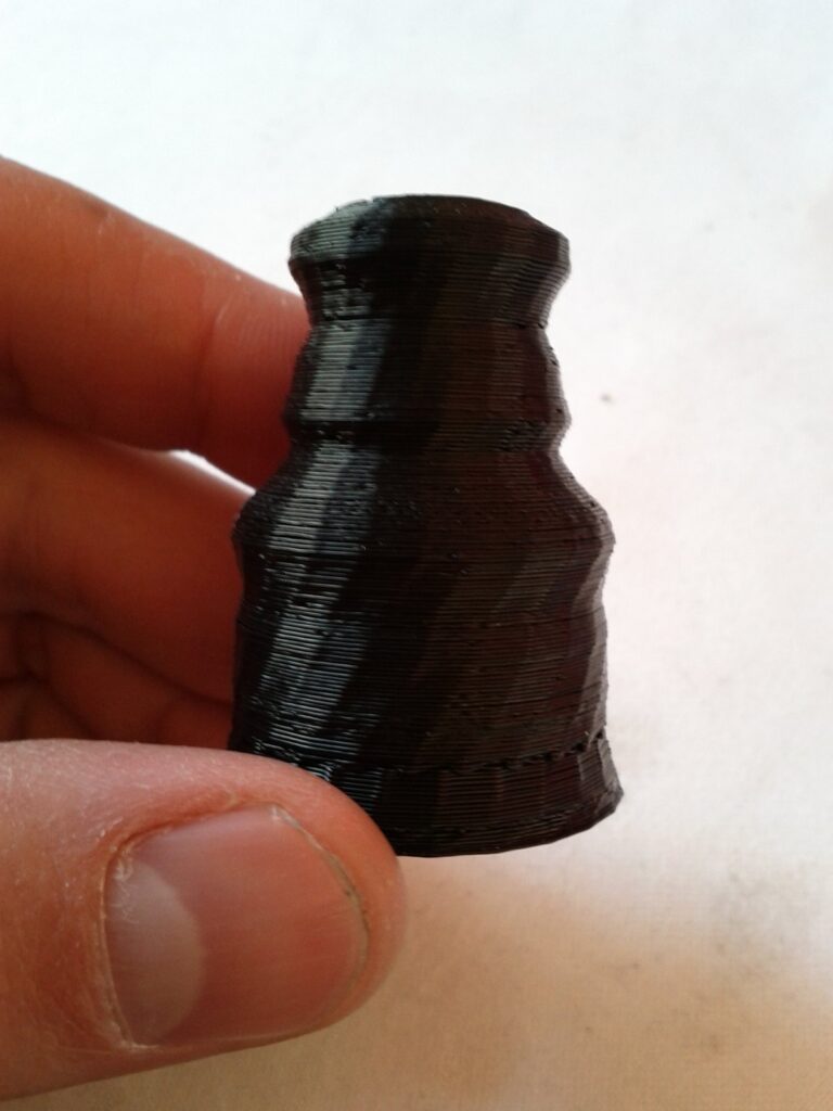 Hand hält eine schwarze Figur aus dem 3D-Drucker, Seitenansicht