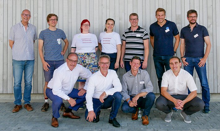 Gruppenfoto der Organisatorinnen und Organisatoren vor einer Holzwand