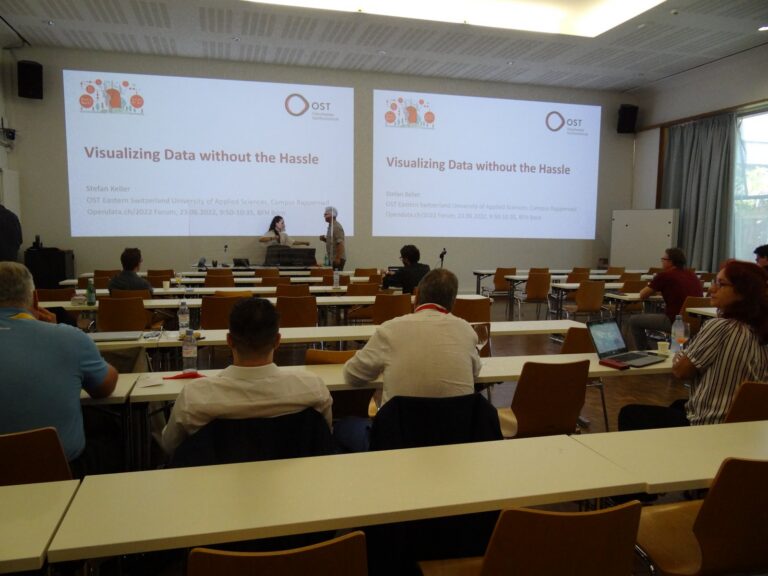 Audience in the main hall, screen reading «Visualizing Data without the Hassle»