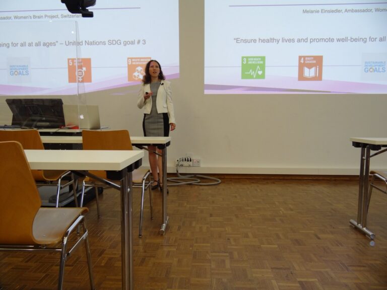 Melanie Einsiedler at the lectern in front of a slide with UN sustainability goals