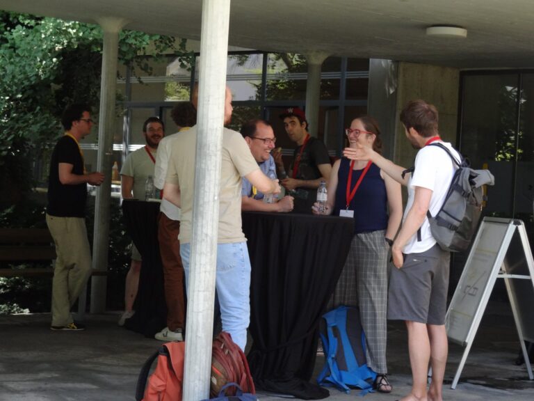 Participants at standing tables under the canopy