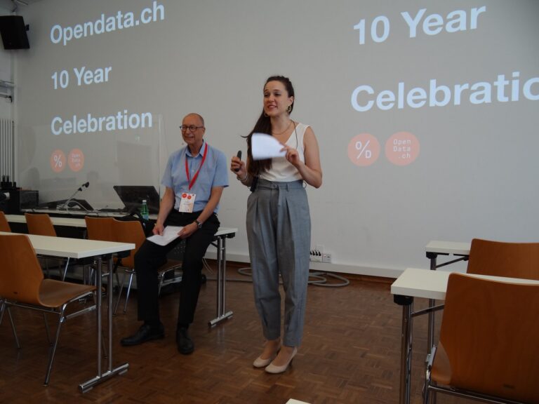 Two hosts in front of the slide «Opendata.ch 10 Year Celebration»