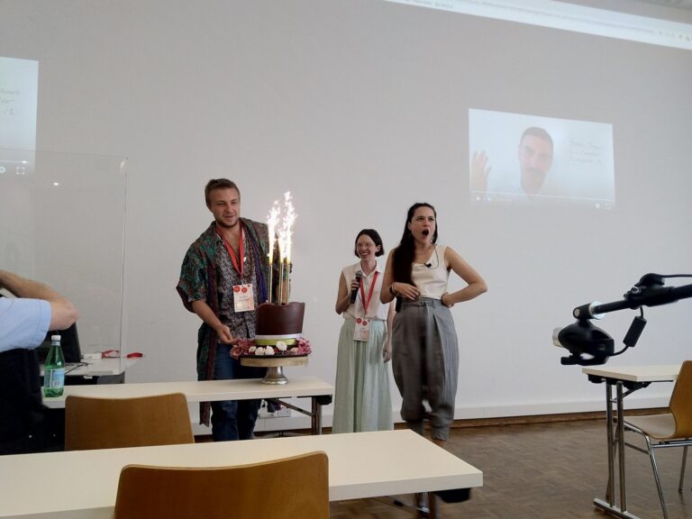Three people next to a chocolate cake with sparklers