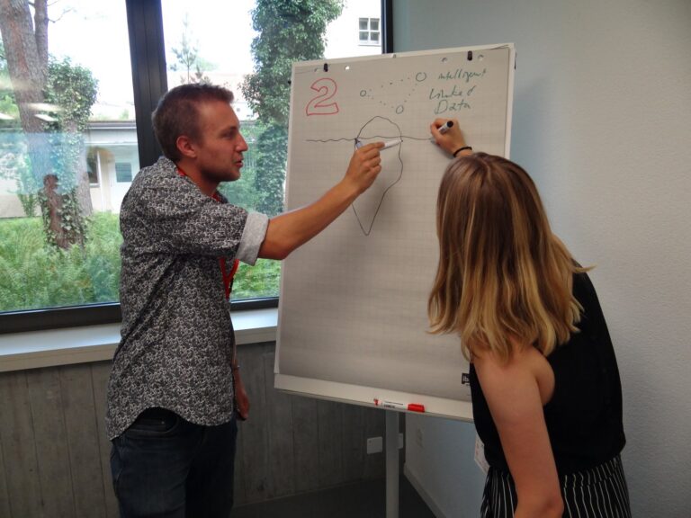 Two people drawing on a flipchart
